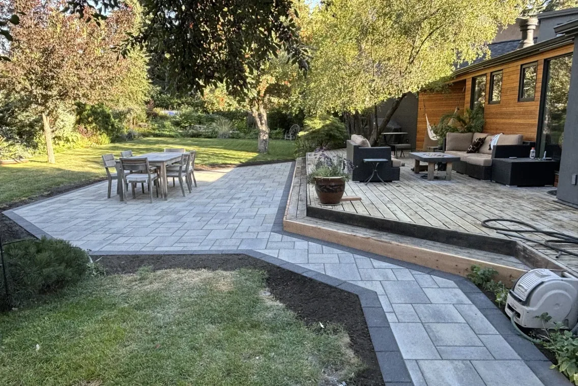 Multi-level paver patio with outdoor dining and lounge seating, cedar home backdrop, Calgary