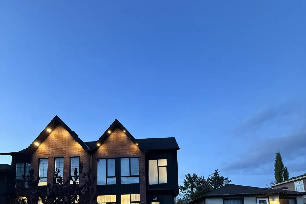 Calgary home exterior beautifully illuminated by professional low-voltage landscape lighting at dusk, All The Moore Landscaping